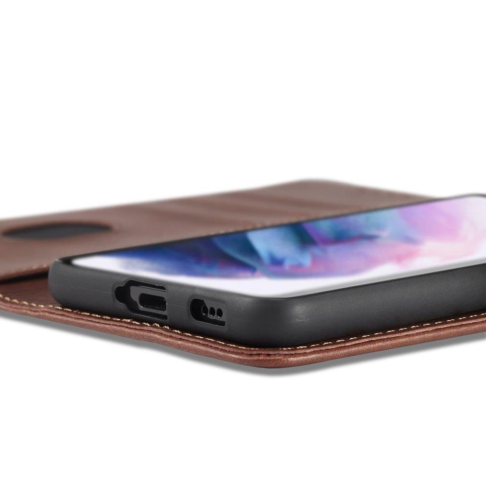 Na obrazie widoczny jest telefon w czarnym etui z klapką, leżący na brązowej powierzchni. Ekran telefonu wyświetla kolorowy wzór.