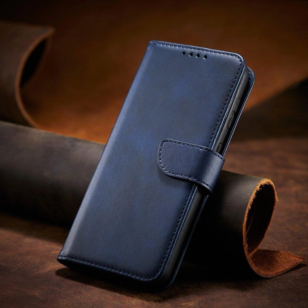 Niebieskie etui na telefon z klapką i funkcją podstawki, wykonane z materiału imitującego skórę. Etui jest zamknięte na magnetyczny pasek i leży na tle z brązowego materiału.
