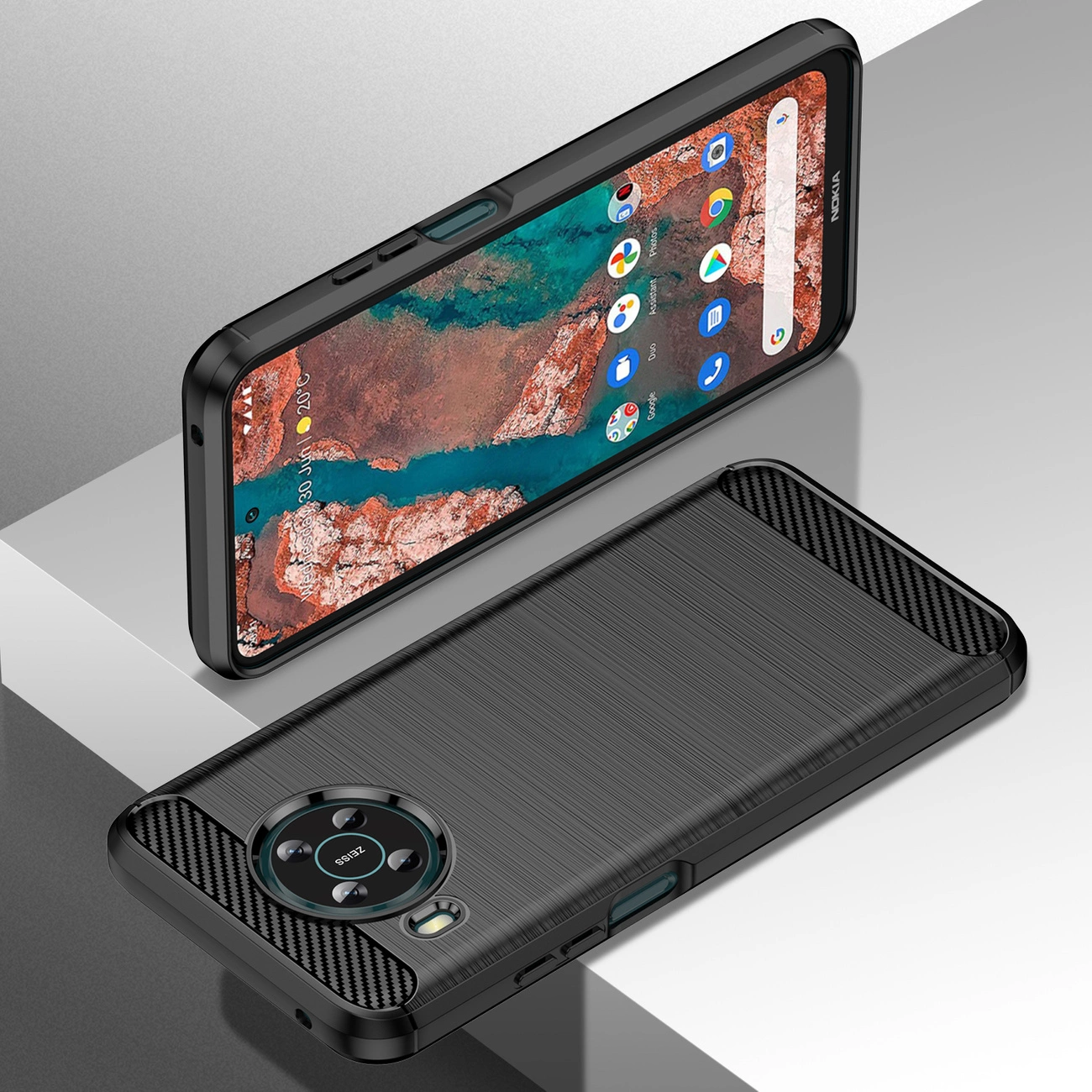 Obraz przedstawia czarne, elastyczne etui na telefon Nokia X100 z teksturą przypominającą włókno węglowe. Etui ma wycięcia na aparat i przyciski, a telefon w nim umieszczony wyświetla ekran główny z ikonami aplikacji.