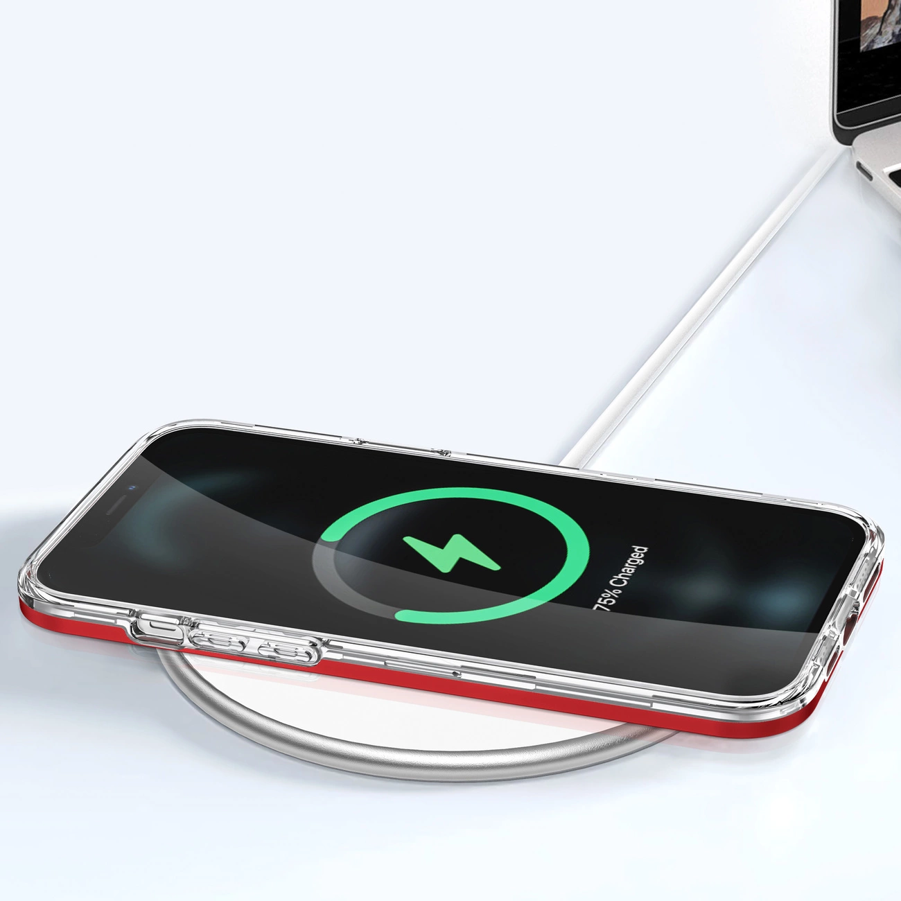 Smartfon w przezroczystym etui z czerwoną ramką leży na ładowarce bezprzewodowej. Na ekranie widoczny jest symbol ładowania i napis \'75% Charged\'.