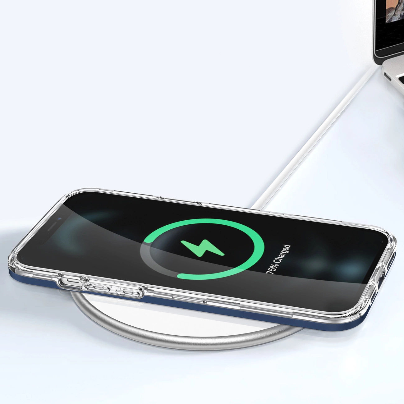 Telefon w przezroczystym etui z niebieską ramką leży na ładowarce bezprzewodowej. Na ekranie widoczny jest symbol ładowania i napis \'75% charged\'.