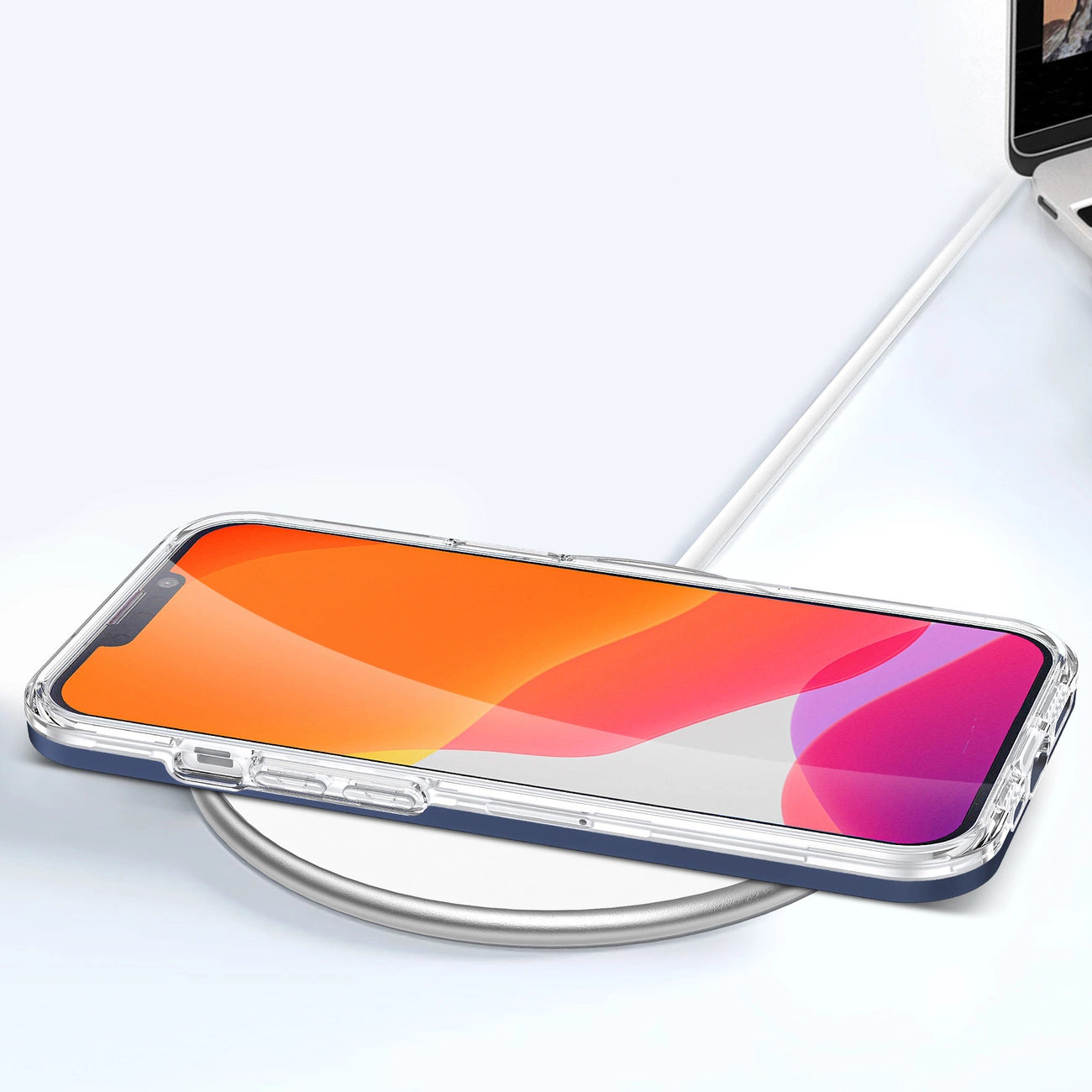 Na obrazie widać smartfon w przezroczystym etui z niebieską ramką, leżący na okrągłej ładowarce bezprzewodowej. Ekran telefonu wyświetla gradientowe tło w odcieniach pomarańczowego i różowego.