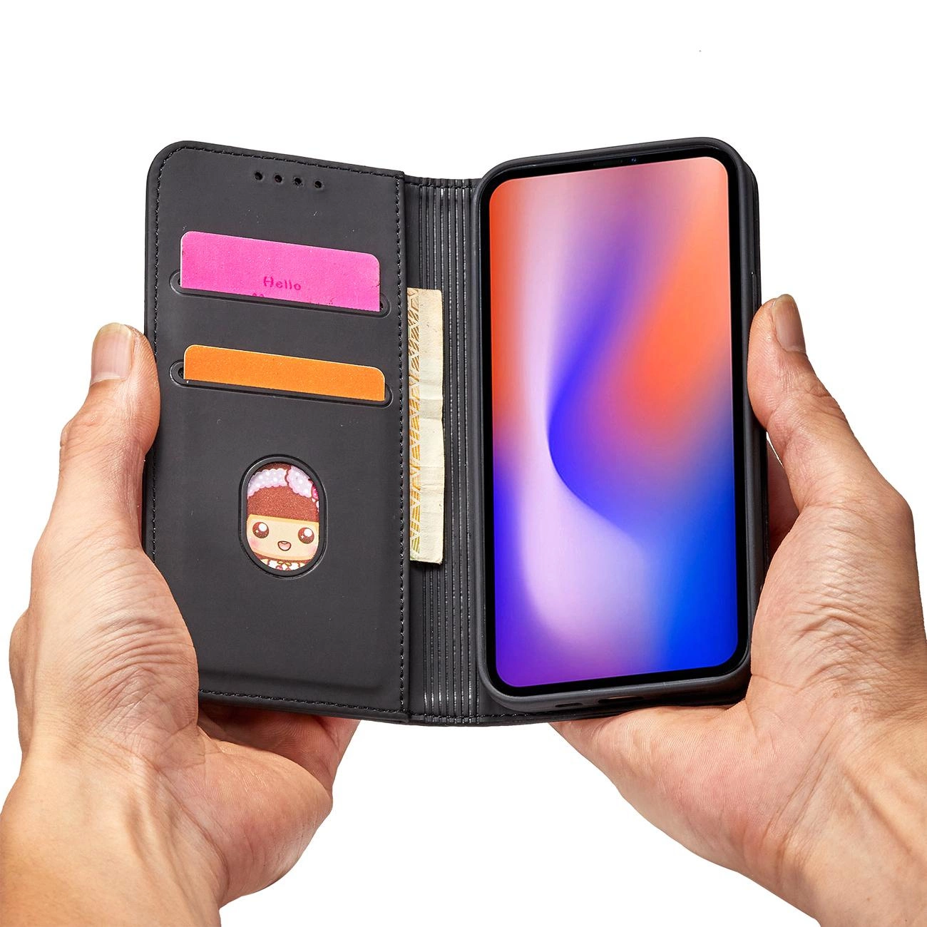 Osoba trzyma czarne etui na telefon z miejscem na karty i banknoty. W etui znajduje się telefon z kolorowym ekranem oraz dwie karty, jedna z napisem \'Hello\'.