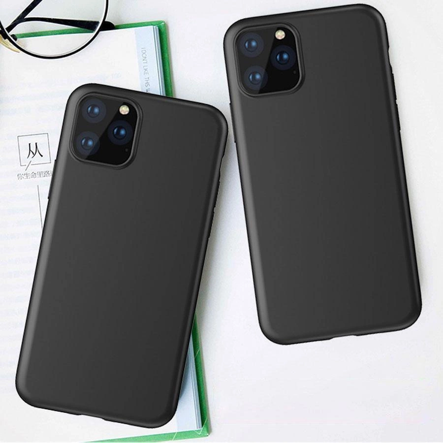 Na obrazie widoczne są dwa czarne etui na telefon z trzema otworami na aparaty fotograficzne. W tle znajduje się otwarta książka i okulary.