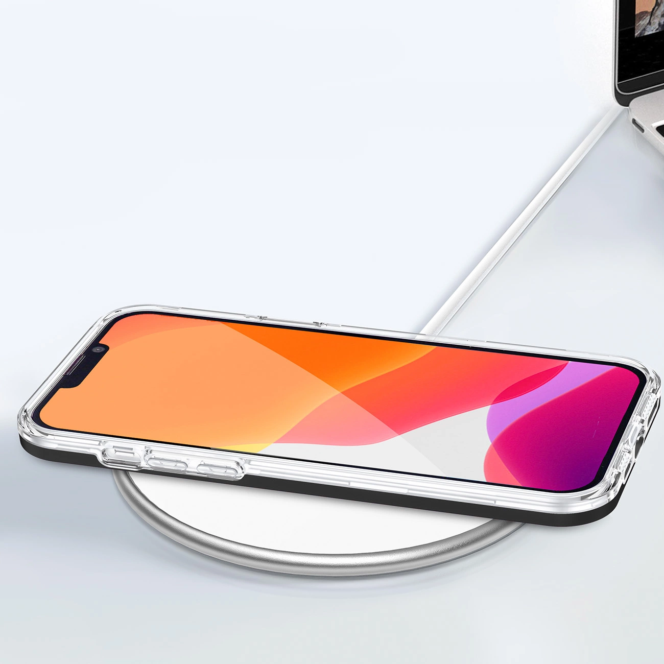 Smartfon w przezroczystym etui z czarną ramką leży na białej, okrągłej ładowarce bezprzewodowej. Ekran telefonu wyświetla gradientowe tło w odcieniach pomarańczu i różu.