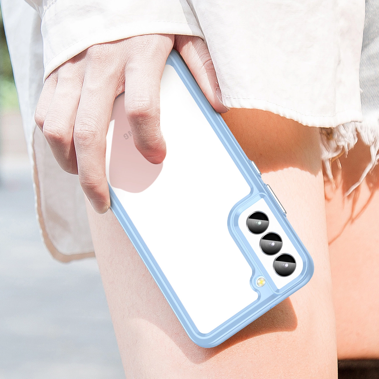 Osoba trzyma telefon w niebieskim etui z trzema widocznymi obiektywami aparatu. Etui ma elastyczną ramkę i jest przejrzyste na tylnej części.