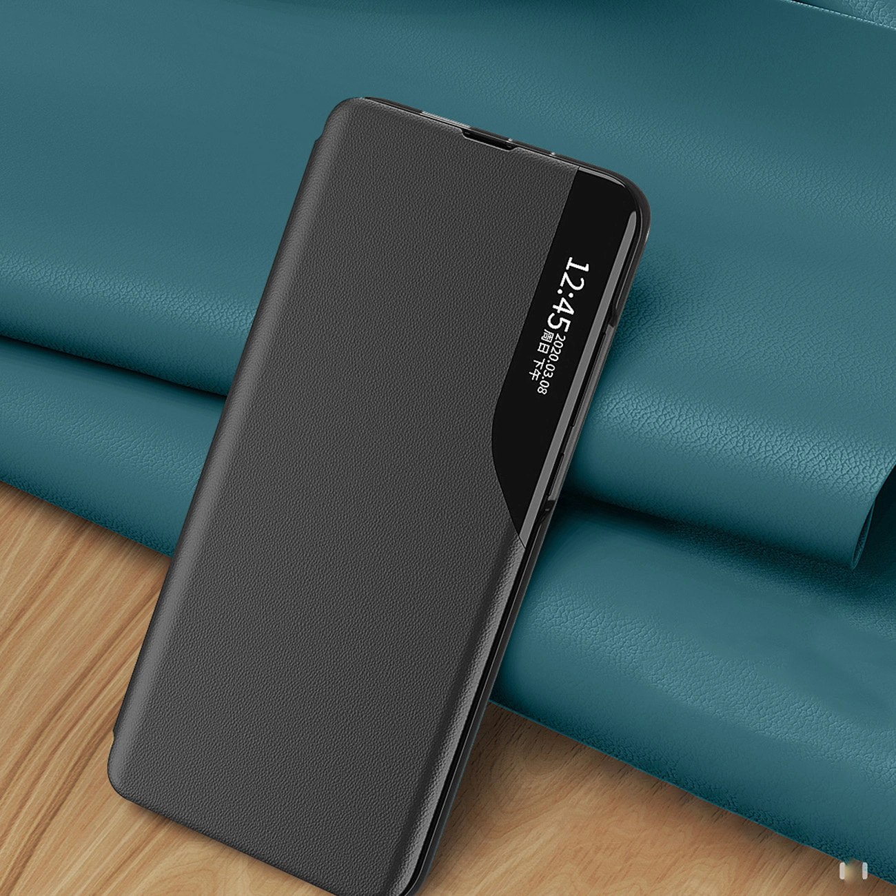 Czarne etui na telefon z klapką, leżące na niebieskim materiale, z widocznym wyświetlaczem pokazującym godzinę 12:45 i datę 2020.08.08.