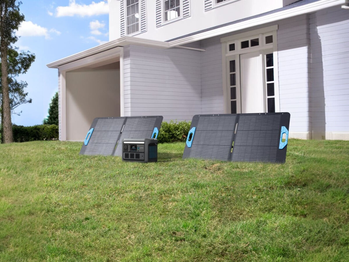 Panel fotowoltaiczny ANKER Solix PS100 100W, MC4, adaptery, bezpieczeństwo, napięcie, Dwa panele ANKER Solix PS100 ustawione na trawie przed domem, obok przenośna stacja zasilająca.