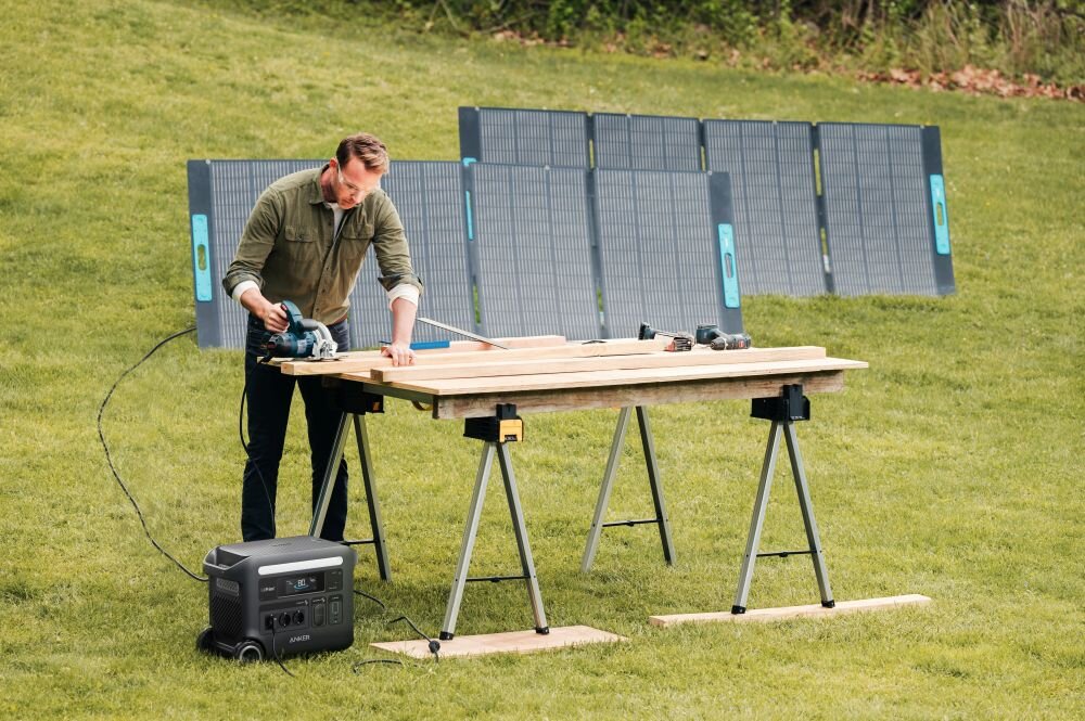 Stacja zasilania ANKER Solix F2600 2560 Wh 2300W, solarne, panele, moc, ładowanie, mężczyzna tnie deski dzięki podłączonemu do stacji pilarce, w tle panele fotowoltaiczne