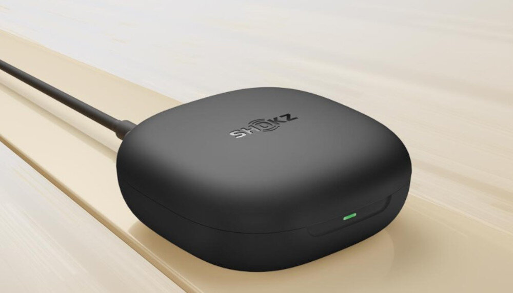 Słuchawki SHOKZ OpenFit 2 11 godzin 48 godzin szybkie ładowanie, etui ładujące leżące na jasnym blacie