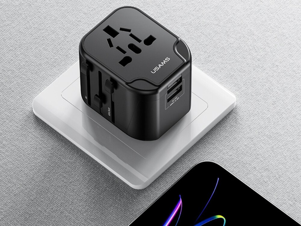 Adapter podróżny USAMS T55 US-CC173 ładowarka 4w1 podróżna Czarny adapter podróżny USAMS wpięty do białego gniazdka ściennego; widoczne uniwersalne wejście na wtyczki oraz dwa porty USB z boku urządzenia.