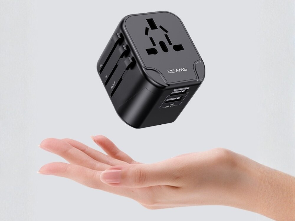 Adapter podróżny USAMS T55 US-CC173 ładowarka 4w1 wtyczki US/AU/EU/UK Kompaktowa przejściówka turystyczna USAMS unosząca się nad otwartą dłonią, podkreślająca lekkość i niewielkie rozmiary produktu.