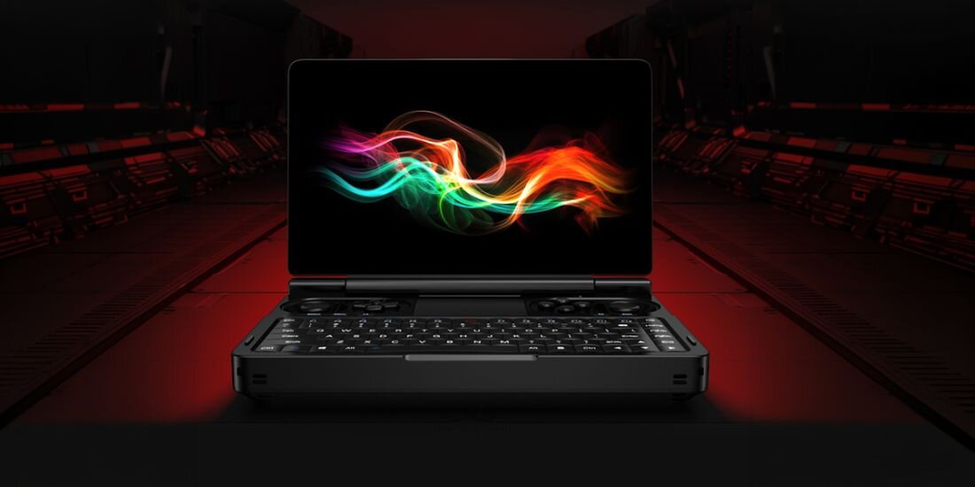 Na obrazie widoczny jest otwarty laptop z kolorowym, abstrakcyjnym wzorem na ekranie. Klawiatura jest podświetlona, a tło jest ciemne z czerwonymi akcentami.