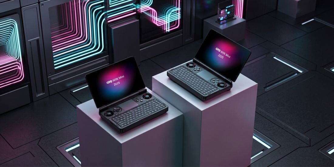 Dwa laptopy z otwartymi ekranami stoją na białych postumentach w futurystycznym pomieszczeniu. Na ekranach widoczny jest tekst: \'GPD Win Mini 2023\'.