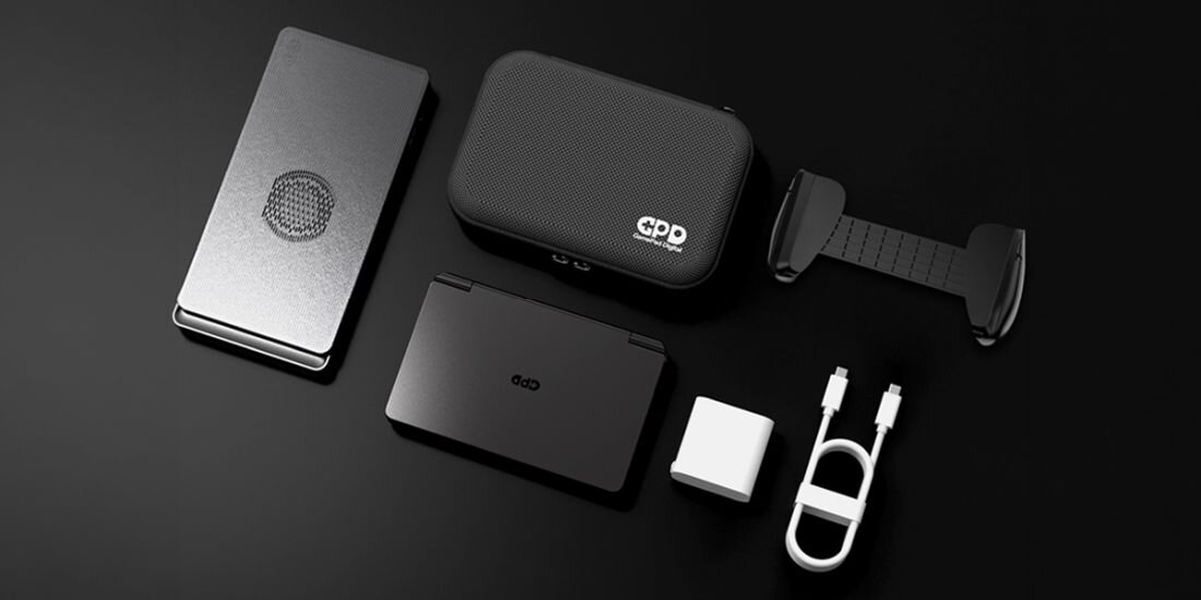 Na czarnym tle widoczne są różne elementy: etui z logo \'GPD\', składany laptop, ładowarka, kabel USB oraz uchwyt. Wszystkie przedmioty są w kolorze czarnym lub białym.