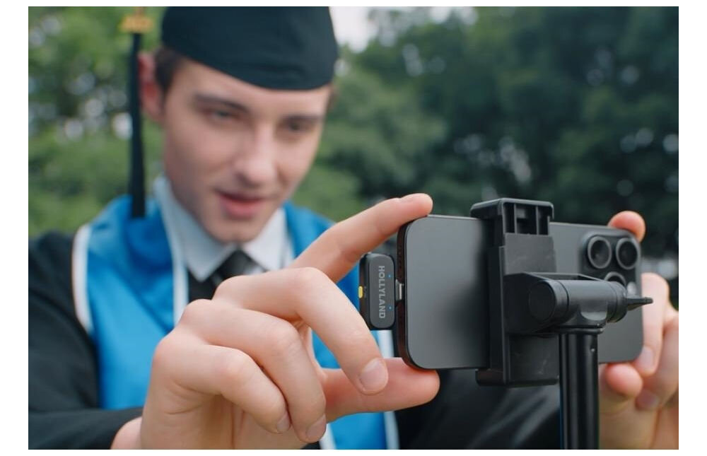 System bezprzewodowy HOLLYLAND Lark A1 Mini Duo USB-C Szary prezentacja zestawu podczas użytkowania uczeń w todze na tle parku trzymający telefon elastyczny system redukcji szumu eliminacja szumów otoczenia trzy poziomy redukcji szumów naturalne klarowne brzmienie głosu