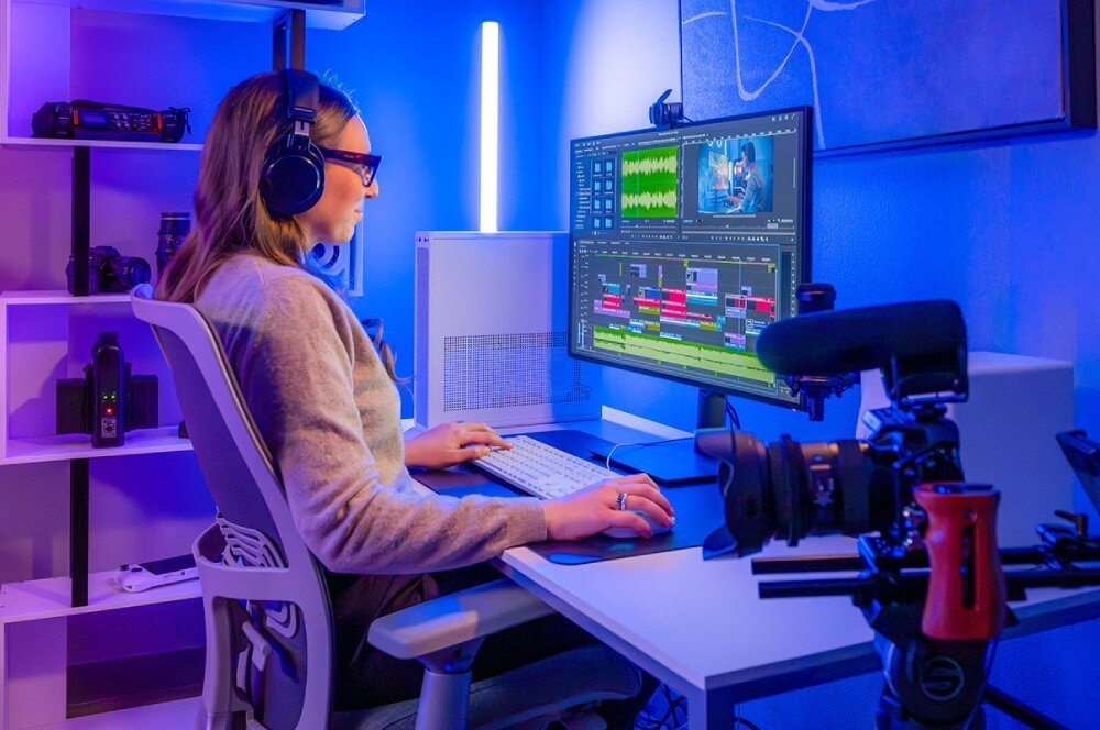 Dysk CRUCIAL T710 Kobieta pracująca przy biurku z dużym monitorem, na którym widoczny jest interfejs programu do montażu wideo, obok kamera i półka ze sprzętem, funkcje, wydajność