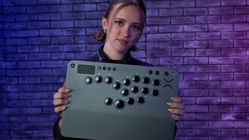 Kontroler TURTLE BEACH PS Victrix Pro Fight Stick Szary prezentacja kontrolera dziewczyna trzymająca go w rękach na tle ciemnego pokoju dla fanów gier walki zawodowy gracz Momochi rozwiązania pomagające skupić się na akcji