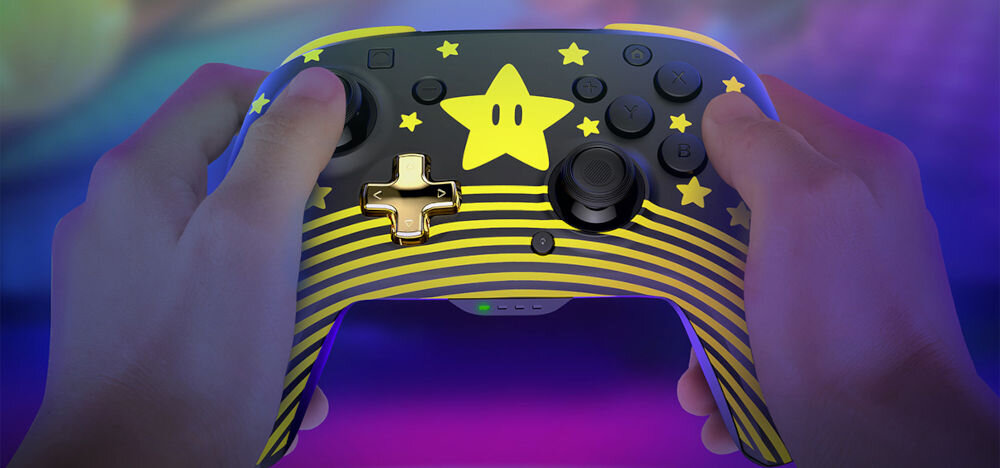 Kontroler TURTLE BEACH Nintendo Switch Rematch Super Mario Star Czarno-żółty prezentacja kontrolera podczas użytkowania ręce na padzie kolorowe tło funkcjonalność efektowny design inspirowany klasykami Nintendo przyjemna gra