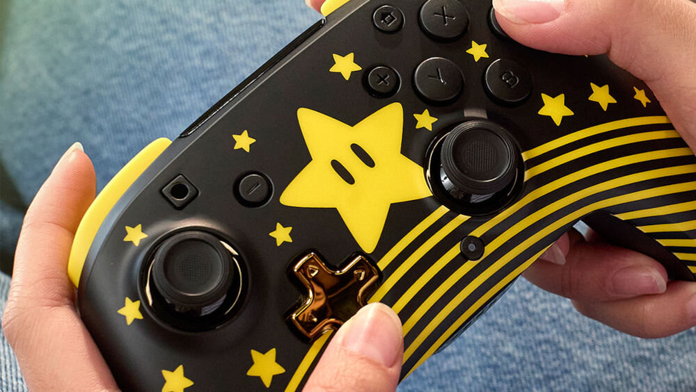 Kontroler TURTLE BEACH Nintendo Switch Rematch Super Mario Star Czarno-żółty prezentacja pada podczas użytkowania ręce na kontrolerze system odwzorowuje ruchy komfort rozgrywki płynna i satysfakcjonująca gra
