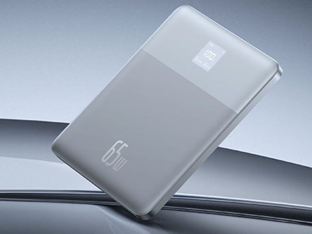 Srebrny powerbank Baseus Blade2 65W z wyświetlaczem 100%, ustawiony pod skosem na błyszczącym metalicznym tle
