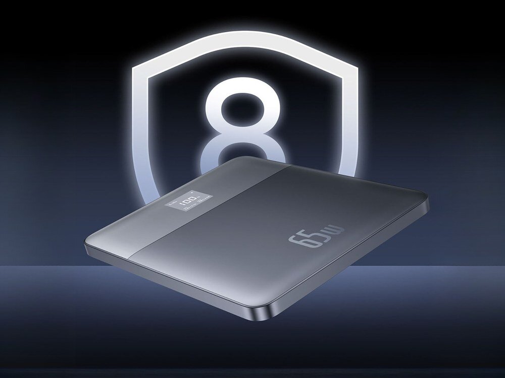 Srebrny powerbank Baseus Blade2 65W z cyfrowym wyświetlaczem, ustawiony pod skosem na tle świecącej ikony tarczy