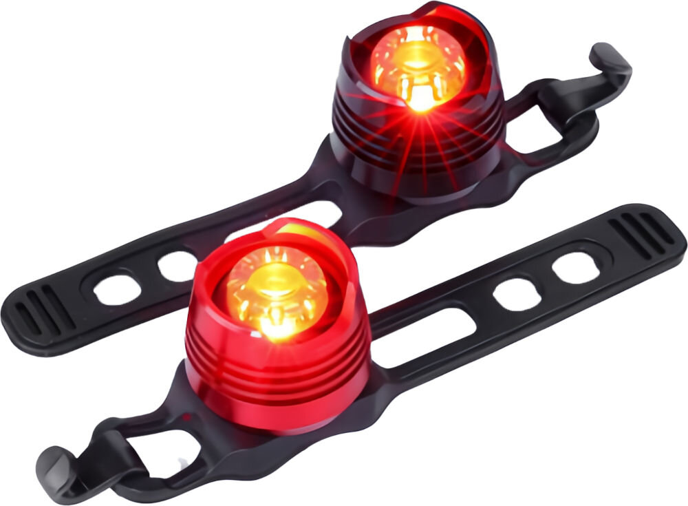 Na obrazie widoczne są dwie czerwone lampki rowerowe z czarnymi uchwytami. Lampki emitują jasne, pomarańczowe światło.