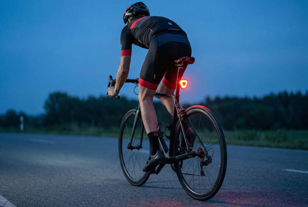 Zestaw lampek rowerowych S-LINE BL605 Przednia lampka rowerowa S-LINE zamontowana na kierownicy typu baranek, oświetlająca ścieżkę w ciemnym, gęstym lesie.