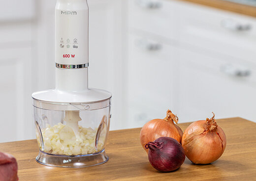 Zbliżenie na blender ręczny MBL-43 z pojemnikiem na kuchennym blacie. W pojemniku posiekana cebula, obok niego całe cebule.