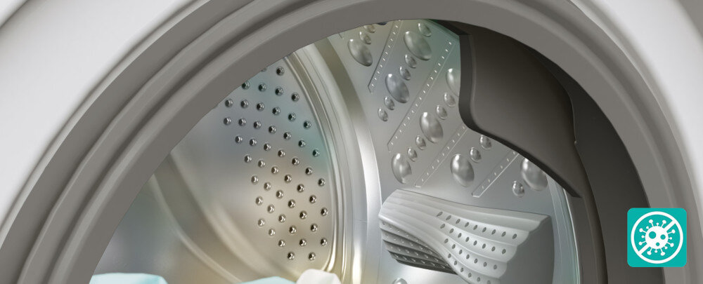 Pralko-suszarka GORENJE G600 WD2PA964ADT/PL Zbliżenie wnętrza bębna pralki pokazuje metalowe ścianki z wypustkami oraz fartuch drzwi, podkreślając higieniczną, łatwą do czyszczenia konstrukcję. W prawym dolnym rogu znajduje się turkusowa ikonka przekreślonego drobnoustroju, symbolizująca ochronę antybakteryjną i ograniczenie rozwoju pleśni oraz bakterii w pralce Antybakteryjna uszczelka higiena czystość bakterie pleśń zapachy świeżość bezpieczeństwo alergicy rodziny