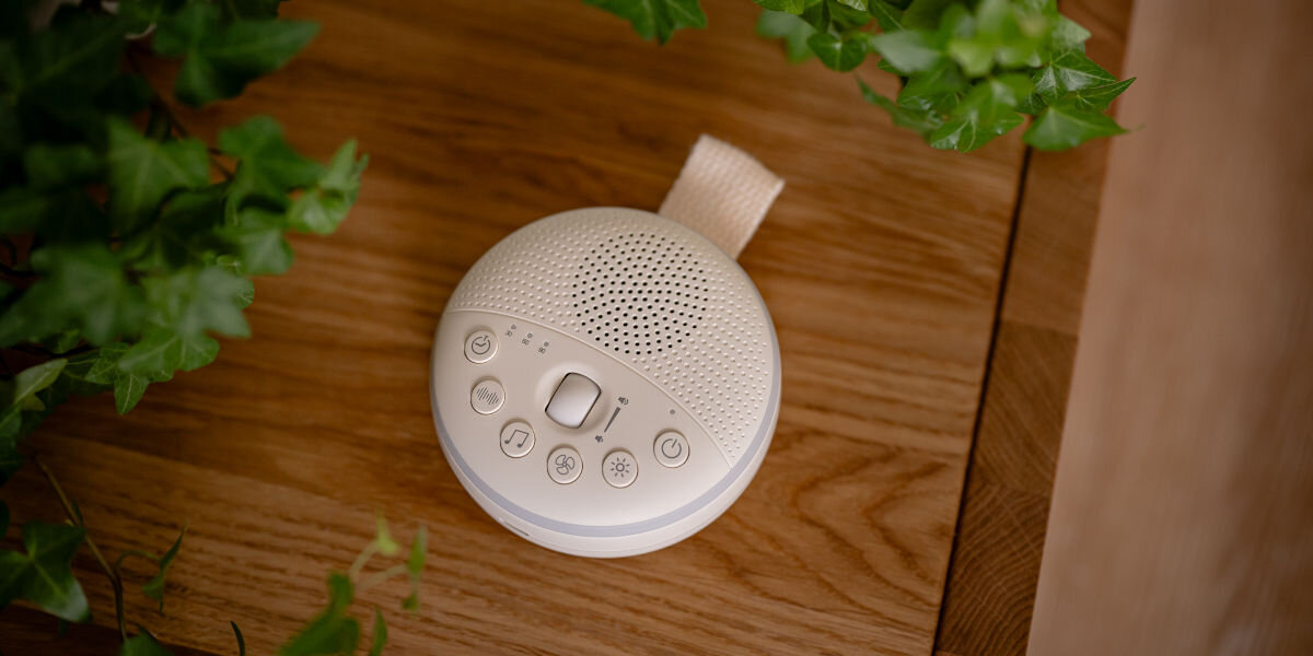 Lampka nocna LED NEWELL LunaWhisper NL4497, relaks, dźwięk, światło, spokój, Lampka stoi na blacie szafki w tle roślinność