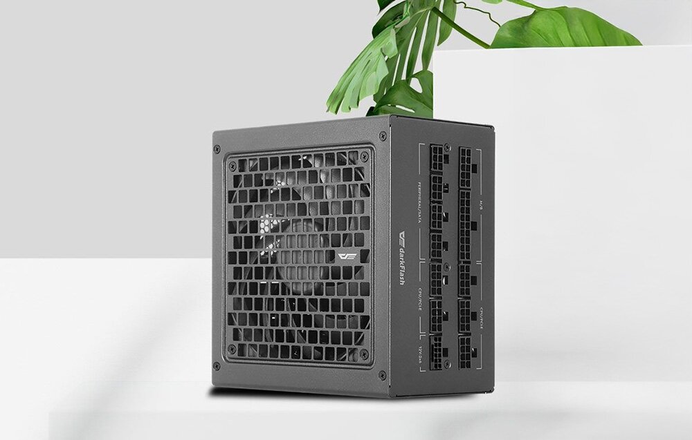 Zasilacz DARKFLASH PMT 850W 80 Plus Gold, ATX 3.1, PCIe 5.1, 12VHPWR, kompatybilność, Modułowy zasilacz na jasnym tle obok zielonej rośliny.