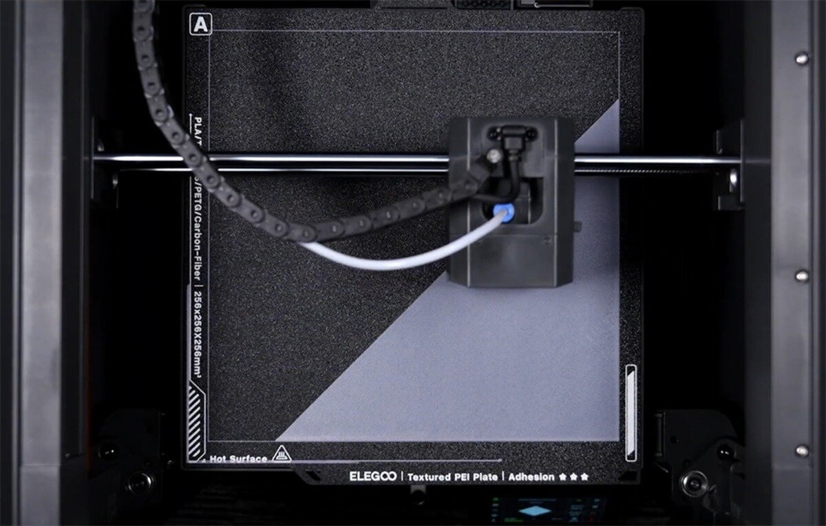 Głowica drukarki 3D na szynie nad płytą Elegoo Textured PEI Plate wewnątrz czarnej obudowy