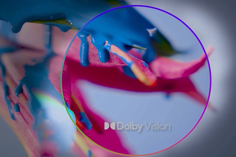 Monitor DELL S3225QC Logo Dolby Vision na tle rozmytego obrazu z kolorowymi elementami w odcieniach różu i błękitu