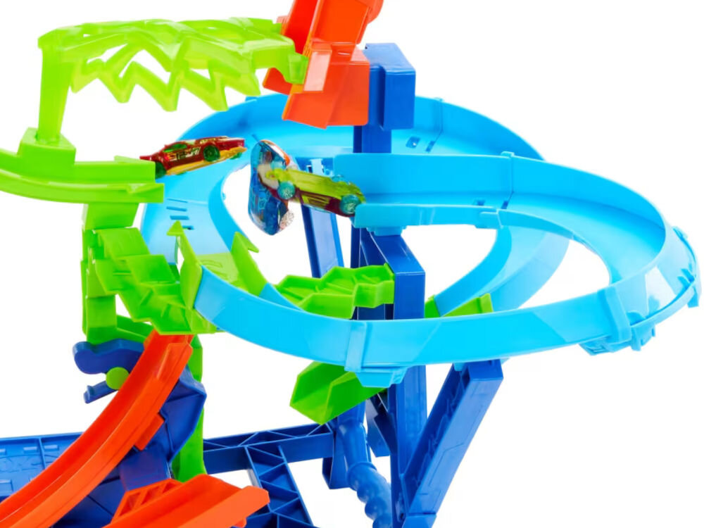 Tor Hot Wheels Stunt Tracks Powietrzna kraksa JFD12 Zbliżenie na środkową część złożonego toru Hot Wheels z dużą niebieską pętlą. Dwa samochodziki (czerwony i zielony) pędzą po torach w różnych kolorach (niebieski, zielony, pomarańczowy). Tło jest białe.