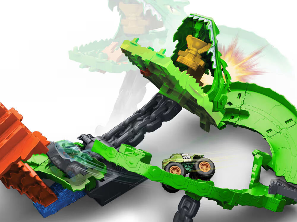 Samochód zdalnie sterowany Hot Wheels Tiger Shark HNV03 Zbliżenie na tor Hot Wheels Monster Trucks Dragon Arena. Zielony samochód monster truck jedzie po zakręcie toru. W otwartej paszczy zielonego smoka widoczne jest złote trofeum. Tło jest białe.