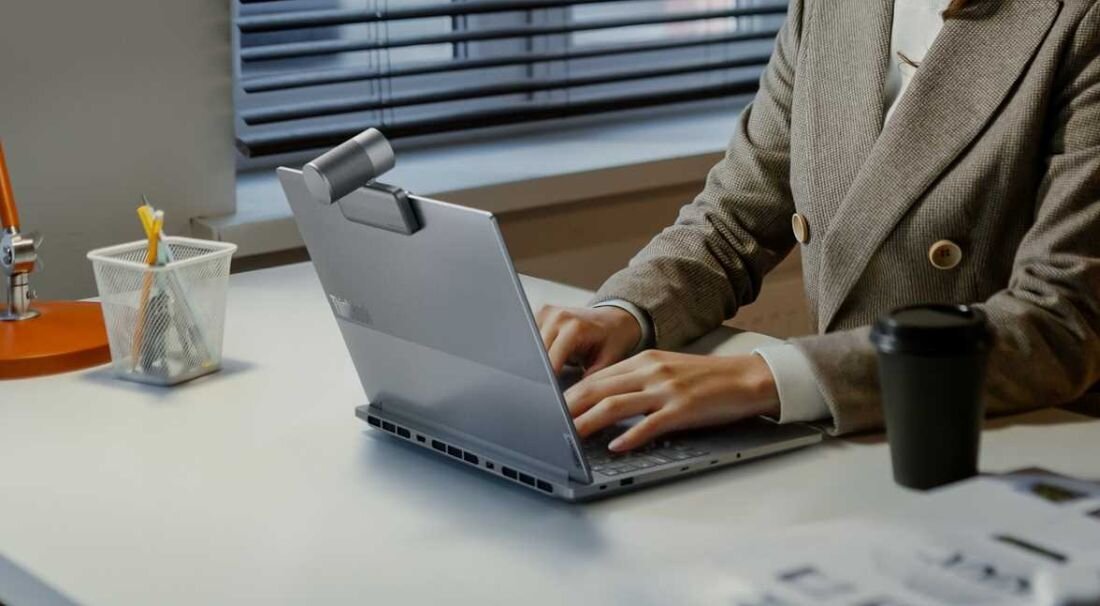 Otwarty laptop Lenovo ThinkBook 16p G6 IAX w kolorze Luna Grey na pastelowym tle; widoczna klawiatura z blokiem numerycznym, duży touchpad i logo Lenovo na pokrywie, smukły profil urządzenia podkreśla jego mobilność i elegancki design - Ogólny opis serii ThinkBook 16p G6 IAX