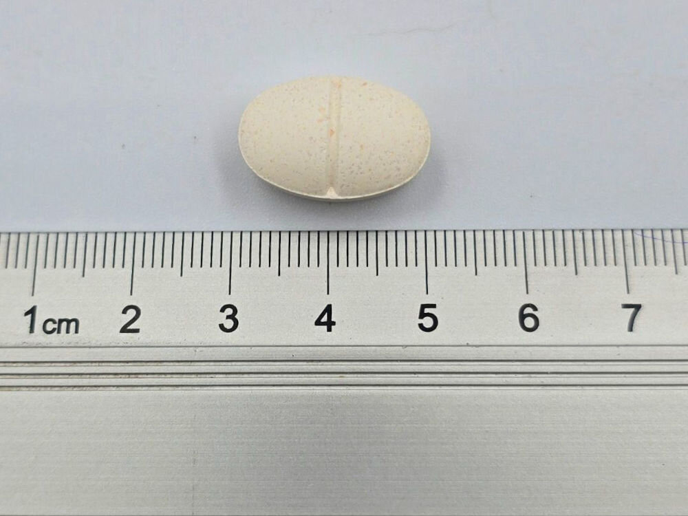 Suplement dla psa GAME DOG AniFlexi Fit V2 (100 kapsułek) Biało-beżowa, owalna tabletka suplementu diety ArthroFlexi z widocznym podziałem (rowkiem) umieszczona na linijce. Tabletka ma długość około 2,5 cm i jest przeznaczona dla psa wspierając stawy i chrząstkę.