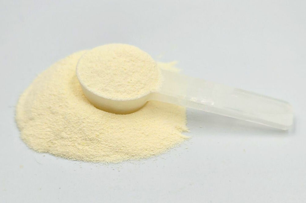 Suplement dla psa GAME DOG IsoDog V2 Nawodnienie izotonik 150 g Biała miarka z proszkiem suplementu IsoDog leżąca na kopczyku preparatu, pokazująca drobną strukturę produktu. 