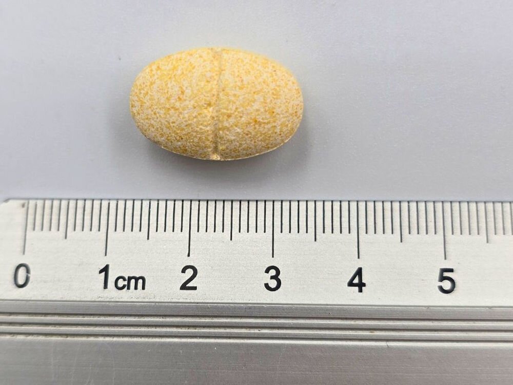 Suplement dla psa GAME DOG Cardio Protect (60 kapsułek) Makro zbliżenie na owalną, żółtą tabletkę suplementu dla psa Cardio Protect umieszczoną na podziałce linijki mierniczej. Tabletkę mierzy około 2,5 cm długości.