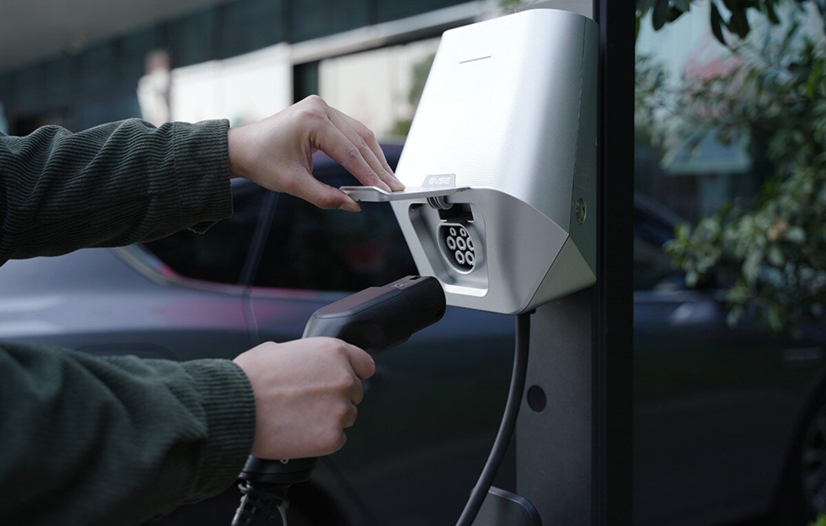 Ładowarka do samochodu elektrycznego BESEN LX30 App 22 kW Osoba podnosząca klapkę gniazda ładowarki EVSE i przygotowująca wtyczkę do podłączenia ładowania.