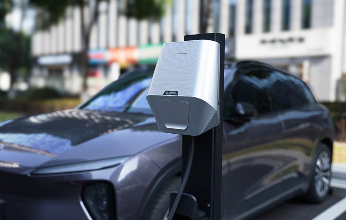 Ładowarka do samochodu elektrycznego BESEN LX30 App 22 kW Srebrna ładowarka EVSE na słupku stojąca na parkingu przed samochodem elektrycznym.