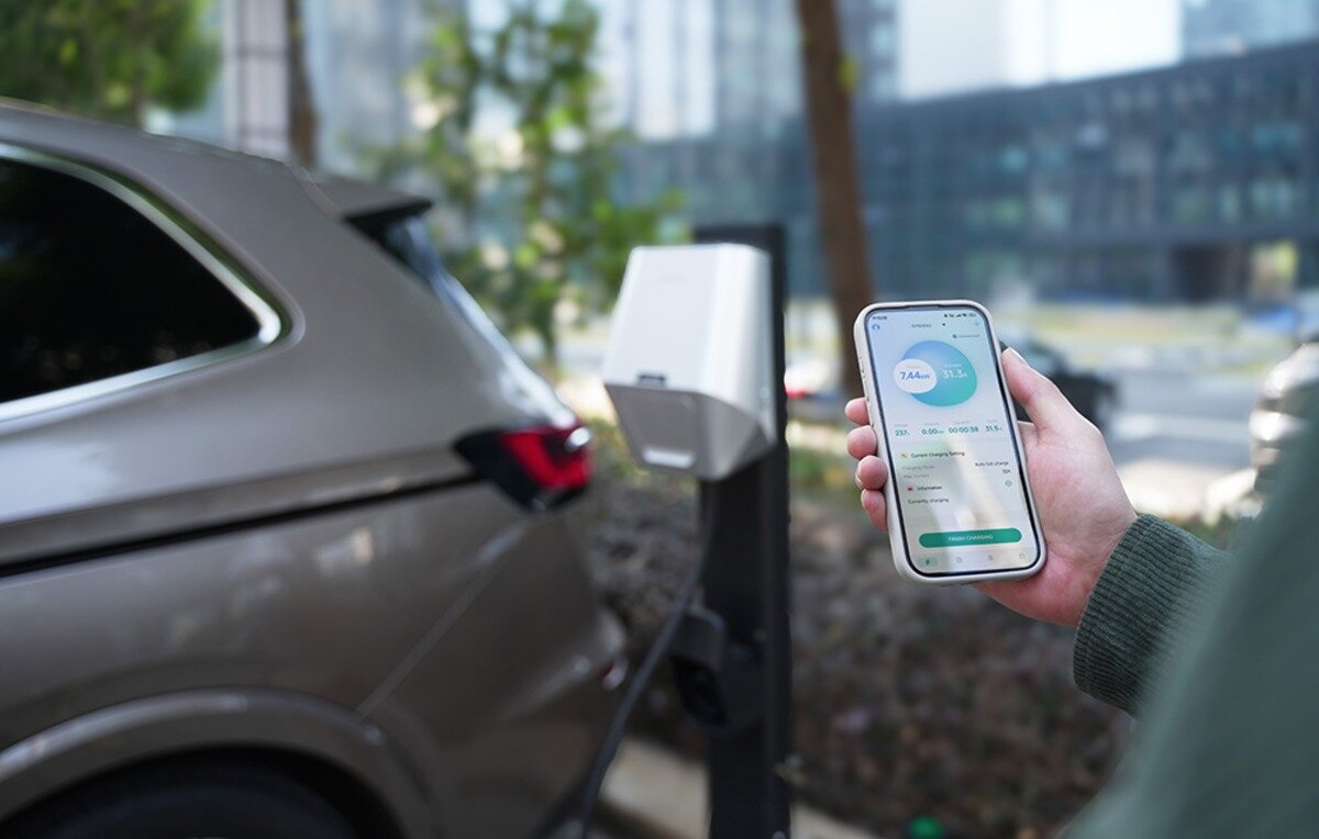 Ładowarka do samochodu elektrycznego BESEN LX30 App 22 kW Ręka trzymająca smartfon z otwartą aplikacją do zarządzania procesem ładowania samochodu elektrycznego.