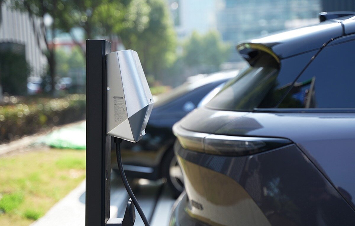 Ładowarka do samochodu elektrycznego BESEN LX30 App 22 kW Srebrna stacja ładowania EVSE zamontowana na czarnym słupku obok zaparkowanego samochodu elektrycznego