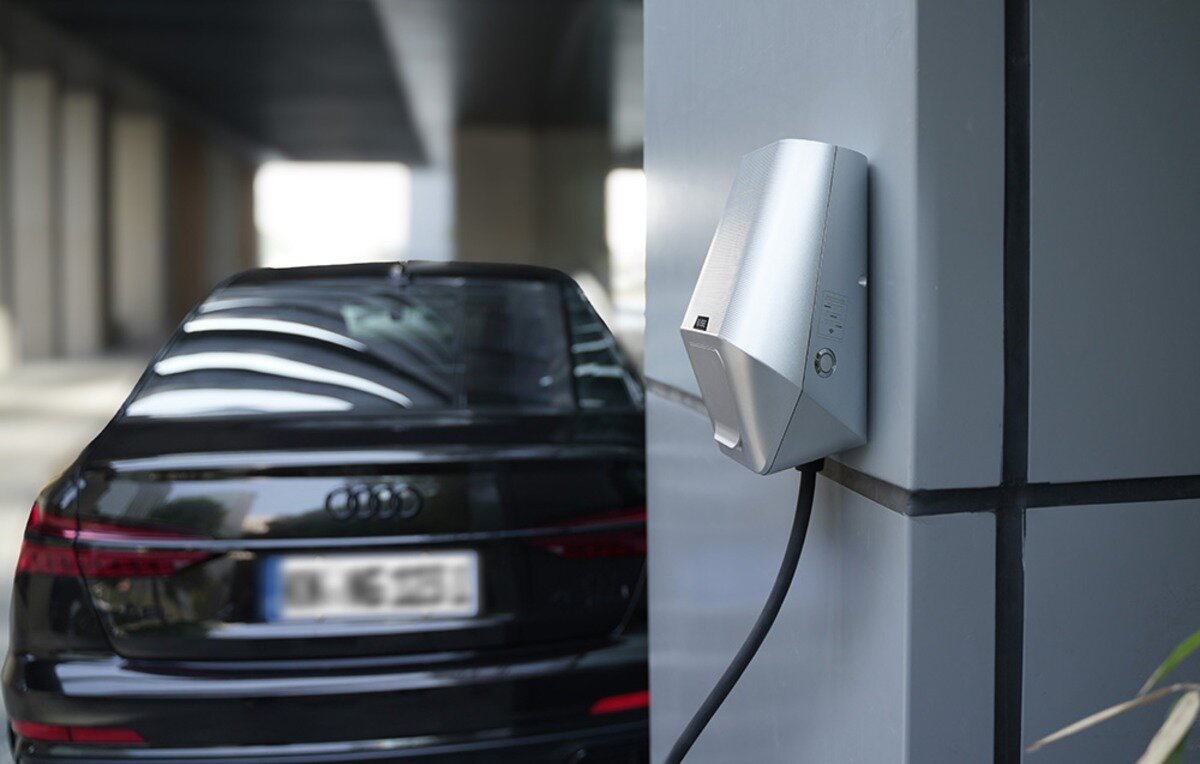 Ładowarka do samochodu elektrycznego BESEN LX30 App 22 kW Ścienna stacja ładowania EVSE zamontowana na szarym filarze budowlanym obok czarnego samochodu marki Audi.