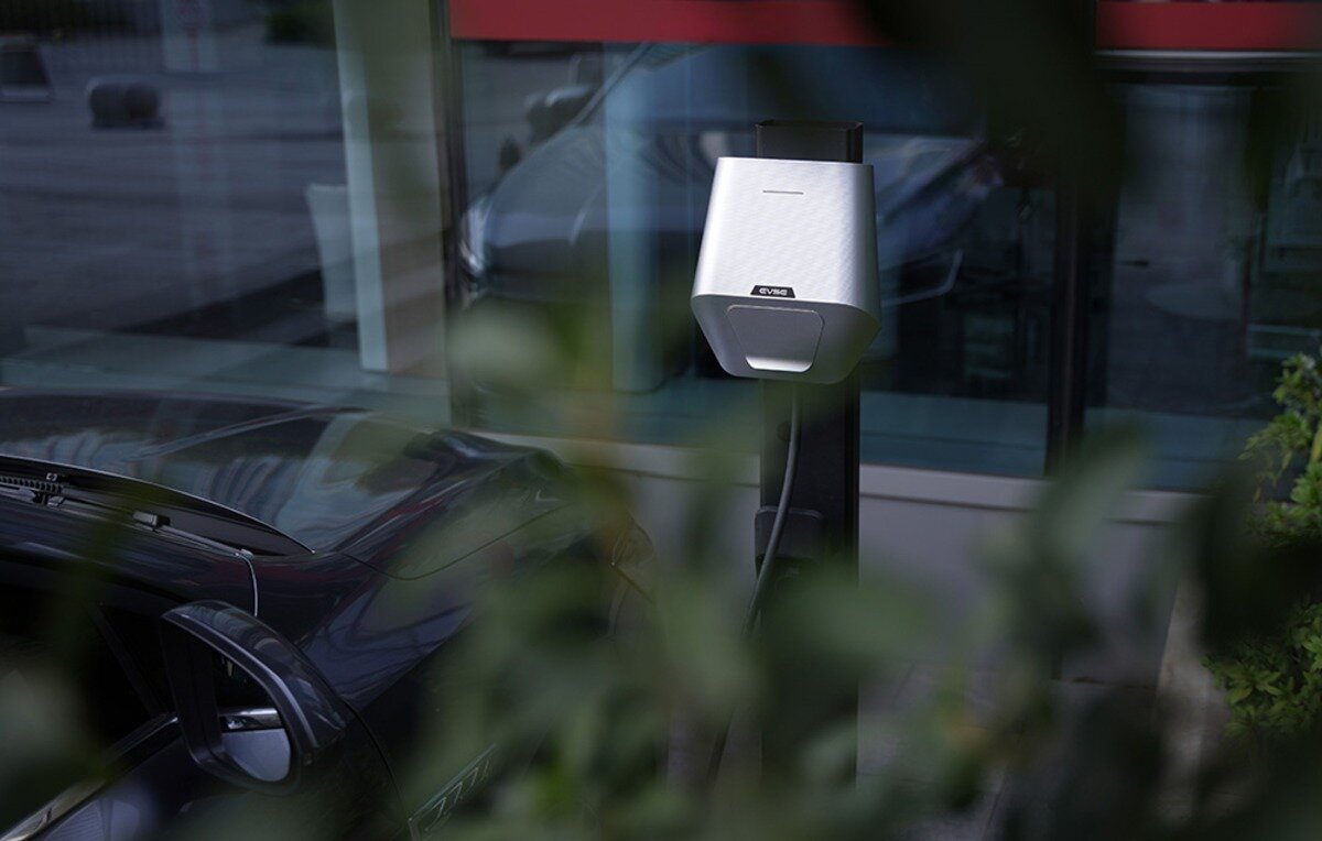 Ładowarka do samochodu elektrycznego BESEN LX30 App 22 kW Stacja ładowania pojazdów elektrycznych EVSE na czarnym słupku stojąca na zewnętrznym parkingu.
