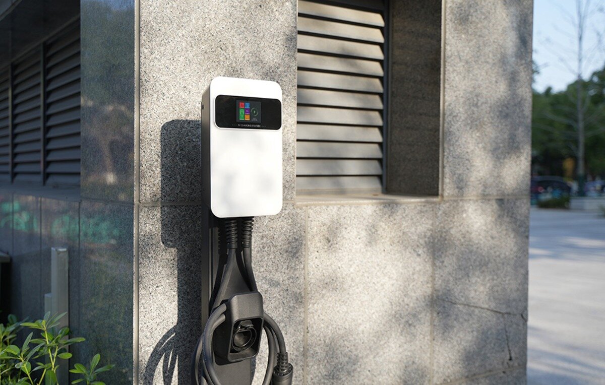 Ładowarka do samochodu elektrycznego BESEN SQ20 App 22 kW stacja ładowania EV z wyświetlaczem i uchwytem na przewód zamontowana przy kamiennej elewacji budynku.