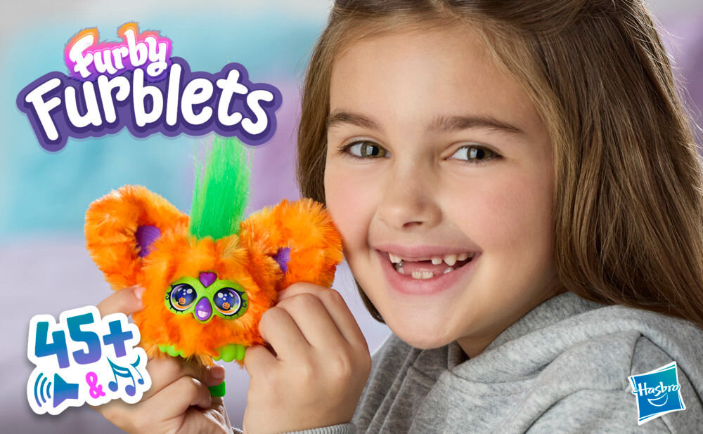 Maskotka HASBRO Furby Furbisie Boo-Kin G14355D0 Uśmiechnięta dziewczynka trzyma przy policzku małą, pomarańczową maskotkę Furby Furblets z zieloną czupryną. Na grafice widoczne logo Furby Furblets, logotyp Hasbro oraz ikona informująca o ponad 45 dźwiękach i melodiach.