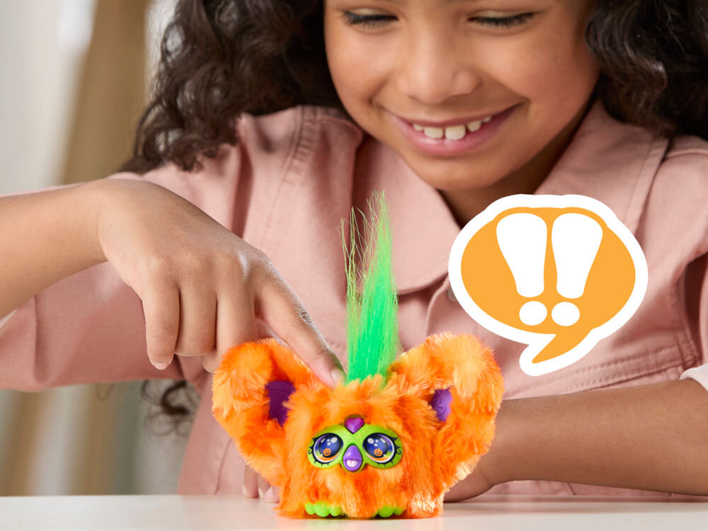 Maskotka HASBRO Furby Furbisie Boo-Kin G14355D0 Zbliżenie na dłoń dziecka naciskającą czubek głowy pomarańczowej maskotki Furby Furblets. Obok widoczna grafika komiksowa z wykrzyknikami, symbolizująca reakcję dźwiękową zabawki.