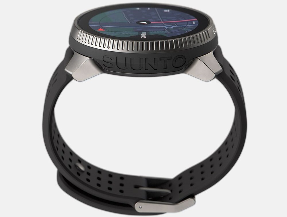 Smartwatch z okrągłym wyświetlaczem, czarnym paskiem i napisem \'SUUNTO\' na obudowie. Na ekranie widoczna jest mapa z czerwonymi i białymi liniami oraz strzałką.